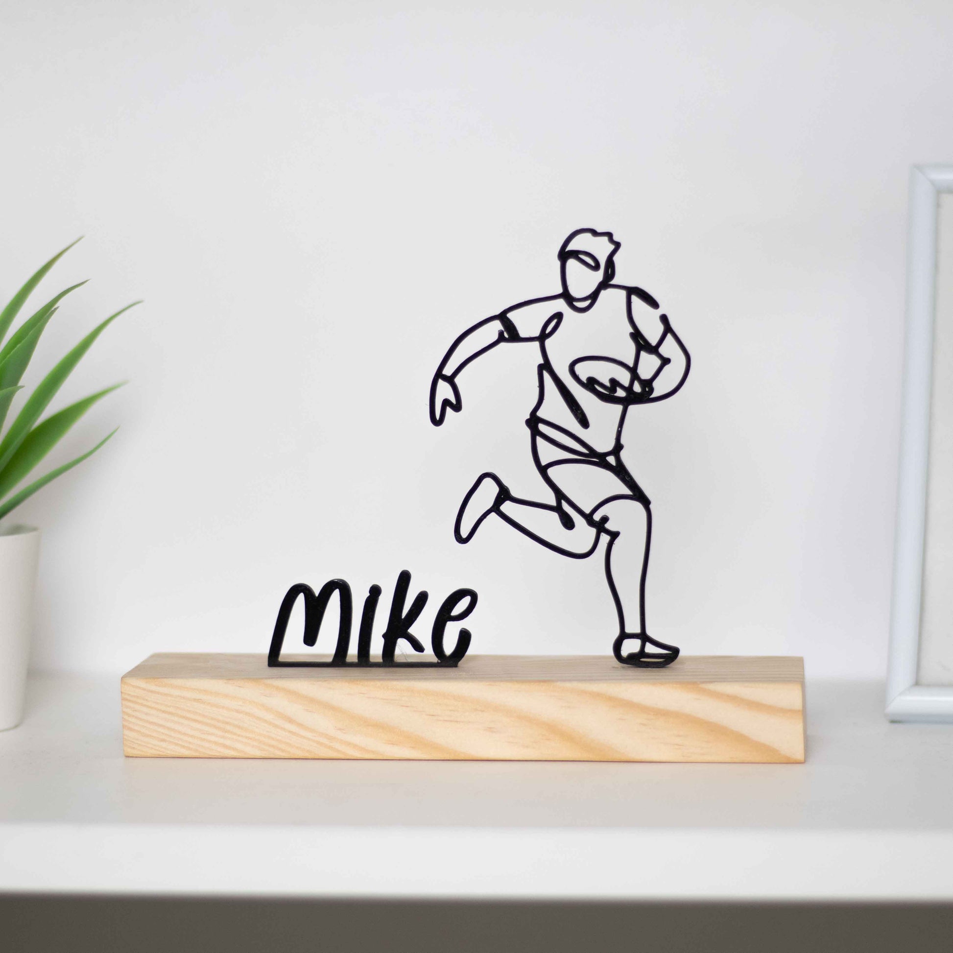 Escultura troféu de jogador de futebol americano em ação, fixada em base de madeira. Perfeita como prémio de competição, presente para atletas ou decoração temática. Personalizável com um nome à escolha.